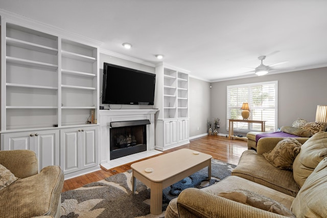 living room with ceiling fan, light hardwood / wood-style flooring, crown molding, and built in features