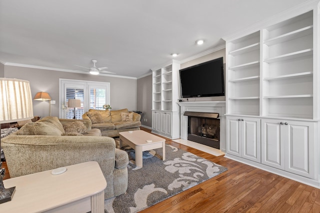 living room featuring ceiling fan, ornamental molding, and light wood-type flooring