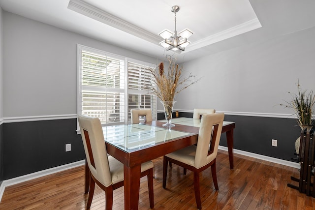 dining room with a tray ceiling, crown molding, dark hardwood / wood-style flooring, and an inviting chandelier