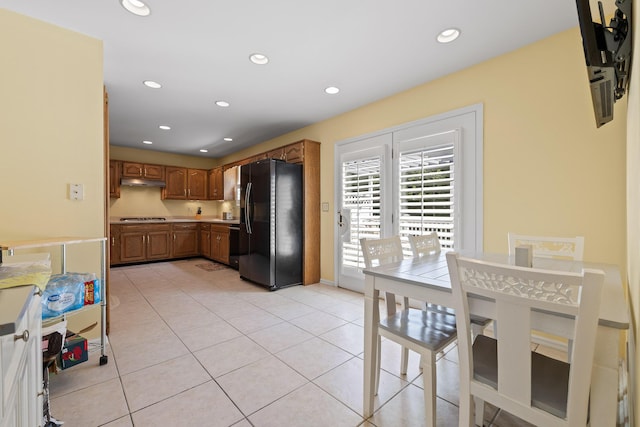 kitchen with cooktop, light tile patterned floors, and black refrigerator with ice dispenser