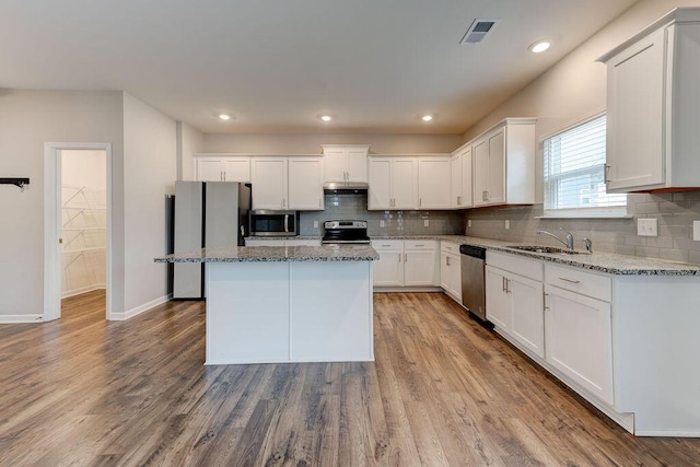 kitchen featuring white cabinets, light wood-type flooring, stainless steel appliances, and a kitchen island