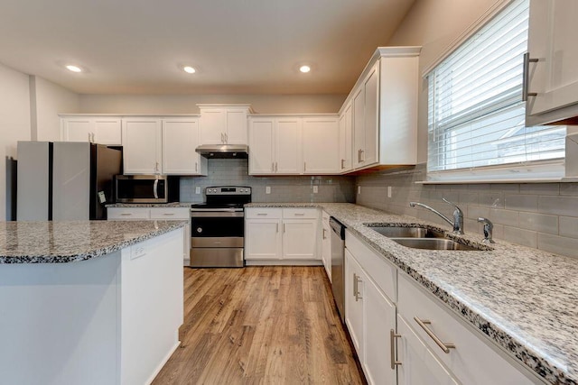 kitchen featuring sink, appliances with stainless steel finishes, light hardwood / wood-style floors, light stone counters, and white cabinetry