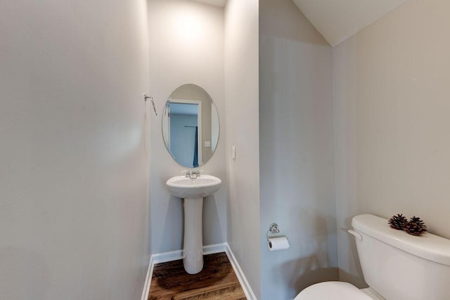 bathroom with hardwood / wood-style floors, toilet, lofted ceiling, and sink