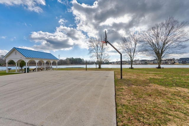 view of property's community with basketball court, a yard, and a water view