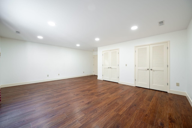 unfurnished bedroom featuring two closets and dark hardwood / wood-style flooring