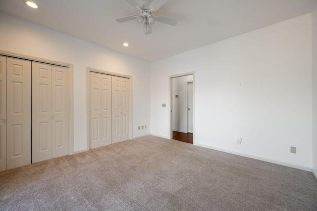 unfurnished bedroom featuring ceiling fan, carpet, and multiple closets