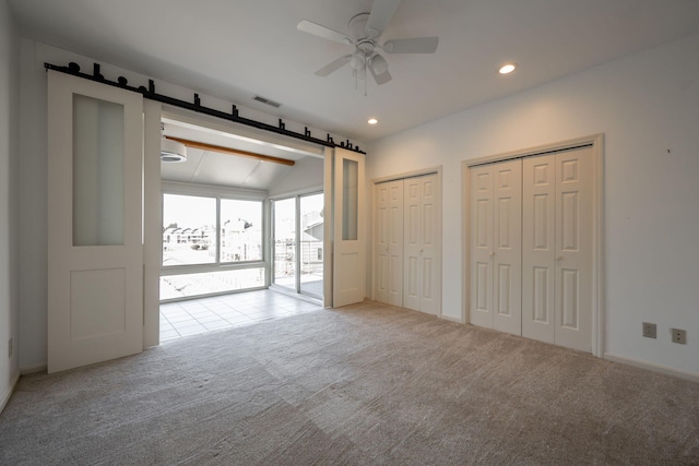 unfurnished bedroom with light carpet, ceiling fan, two closets, and vaulted ceiling with beams