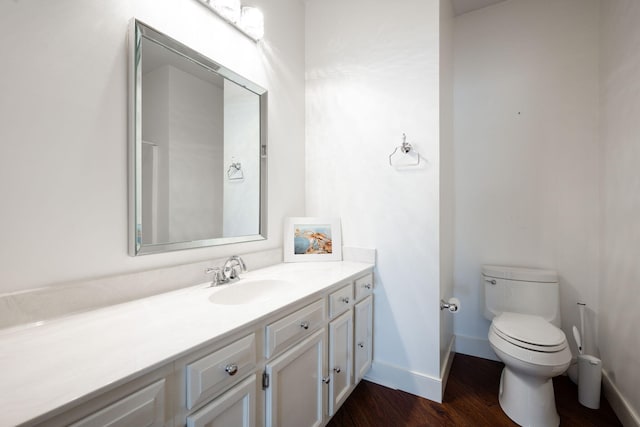 bathroom with toilet, vanity, and hardwood / wood-style floors