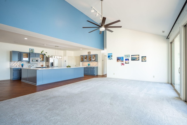 unfurnished living room featuring ceiling fan, high vaulted ceiling, and dark colored carpet