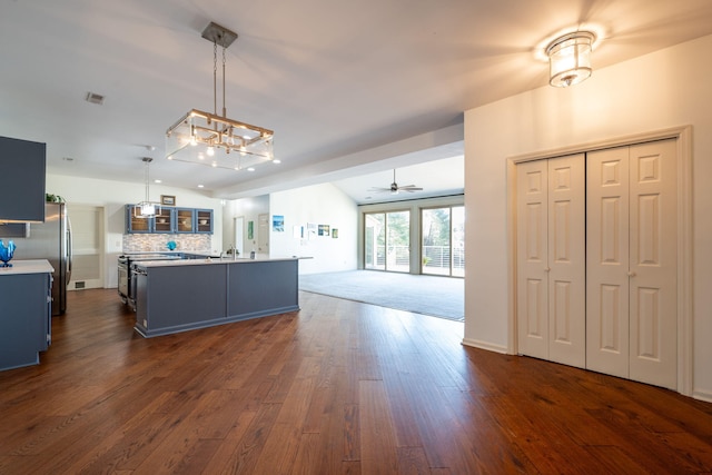 kitchen featuring a center island with sink, ceiling fan, decorative backsplash, dark hardwood / wood-style flooring, and hanging light fixtures