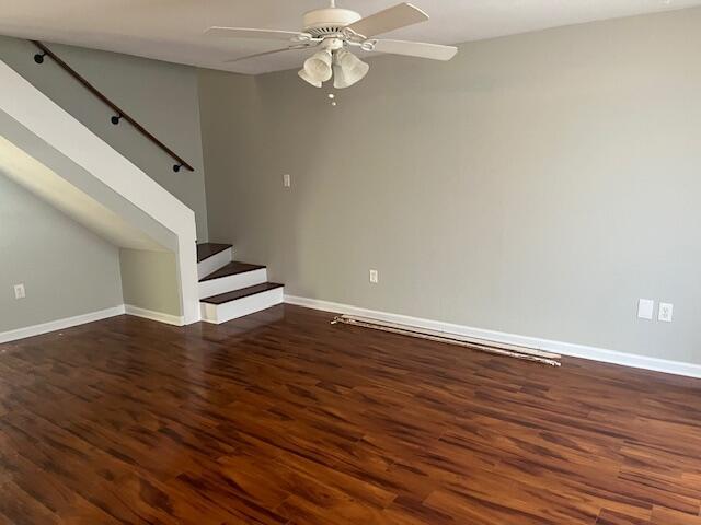 unfurnished living room featuring dark hardwood / wood-style flooring and ceiling fan