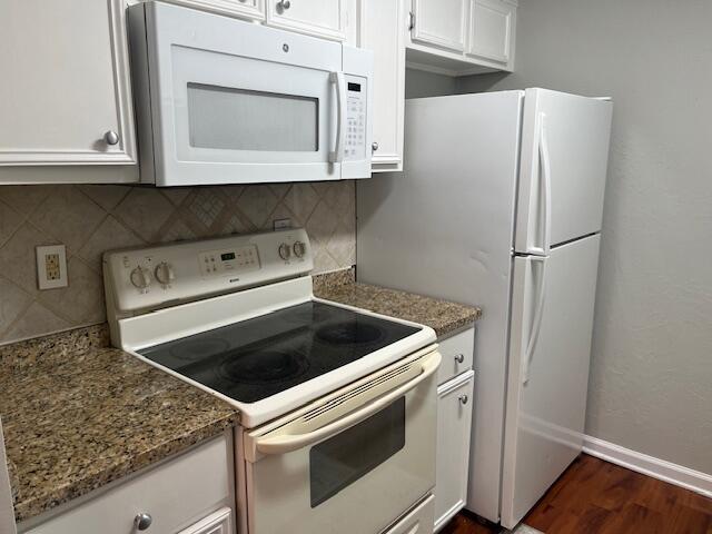 kitchen featuring decorative backsplash, white cabinetry, dark wood-type flooring, and white appliances