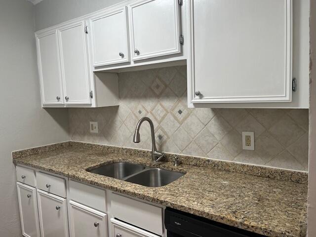 kitchen with backsplash, sink, black dishwasher, stone countertops, and white cabinetry