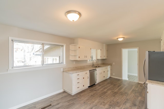 kitchen with appliances with stainless steel finishes, sink, white cabinets, and light hardwood / wood-style floors