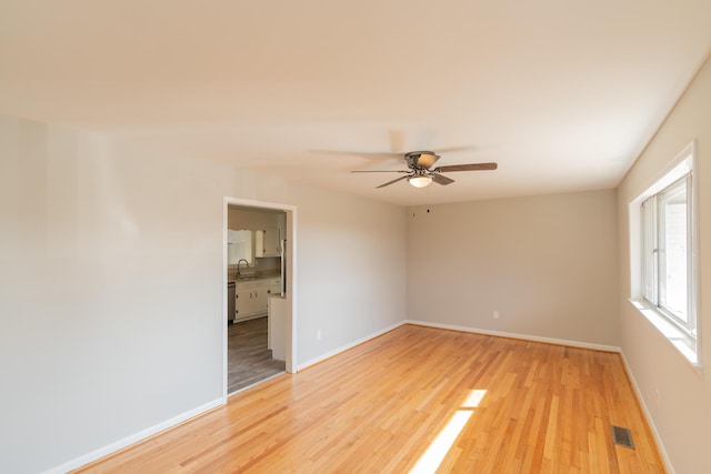 empty room with sink, light hardwood / wood-style flooring, and ceiling fan