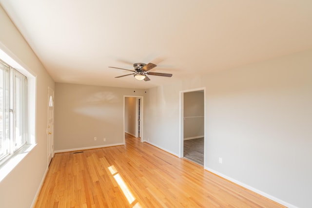 empty room with ceiling fan and light hardwood / wood-style flooring