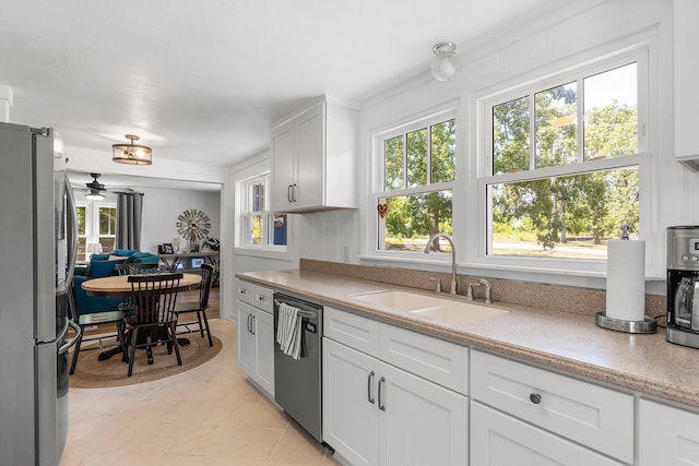 kitchen with stainless steel appliances, ceiling fan, sink, white cabinetry, and light tile patterned flooring