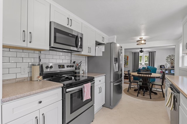 kitchen with white cabinets, decorative backsplash, ceiling fan, and stainless steel appliances