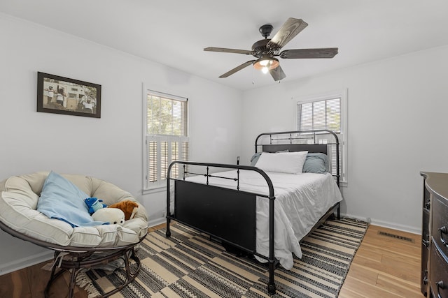 bedroom with hardwood / wood-style floors, ceiling fan, and multiple windows