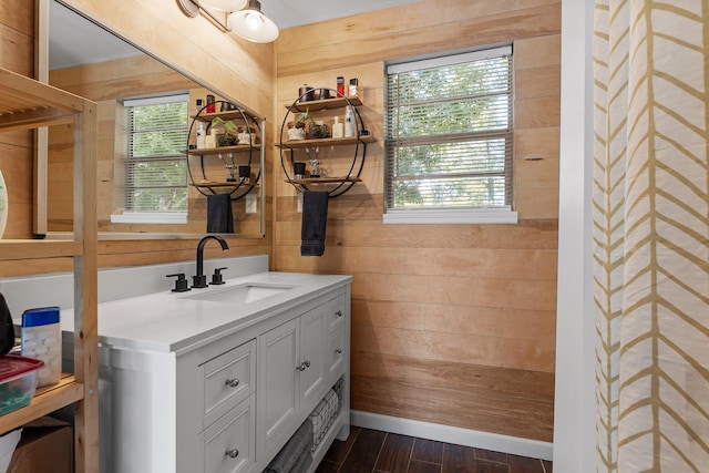 bathroom featuring a wealth of natural light, wooden walls, and vanity