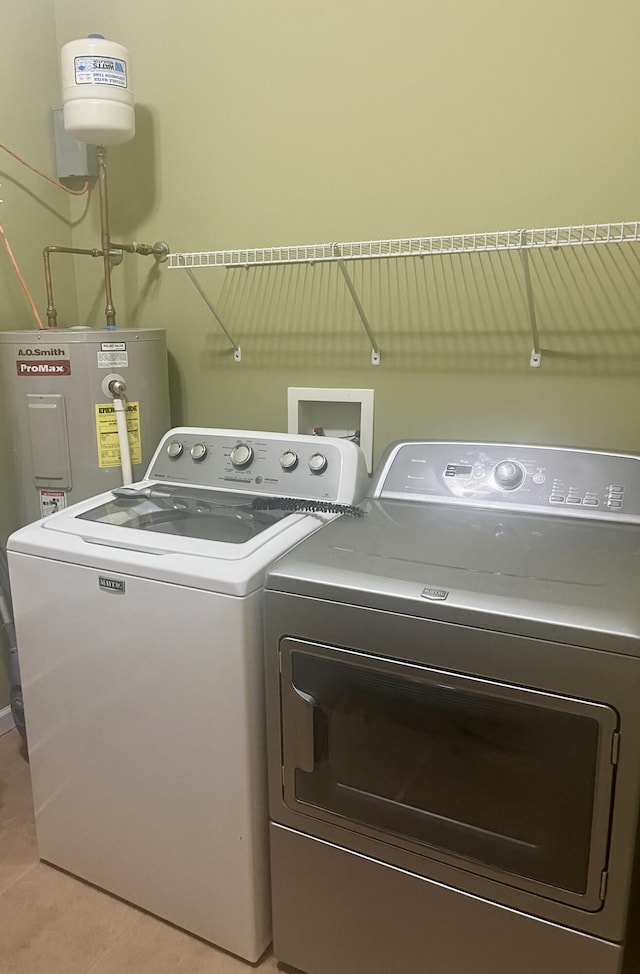 washroom with washer and clothes dryer, light tile patterned floors, and water heater