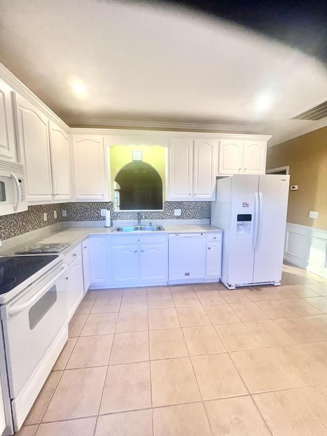 kitchen with white appliances, backsplash, white cabinetry, and sink