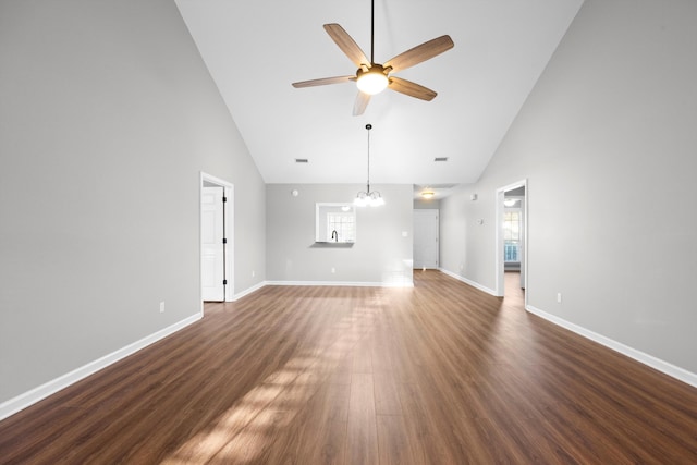 unfurnished living room with dark hardwood / wood-style floors, ceiling fan with notable chandelier, and high vaulted ceiling