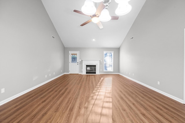 unfurnished living room featuring ceiling fan with notable chandelier, hardwood / wood-style flooring, high vaulted ceiling, and a premium fireplace