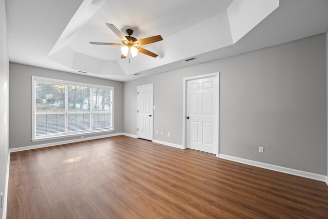 unfurnished room featuring dark hardwood / wood-style flooring, a raised ceiling, and ceiling fan