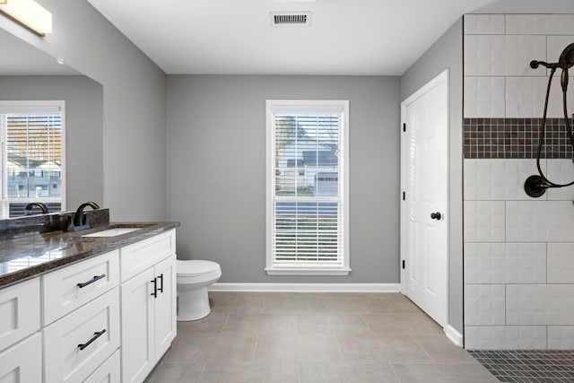 bathroom with tiled shower, tile patterned floors, vanity, and toilet