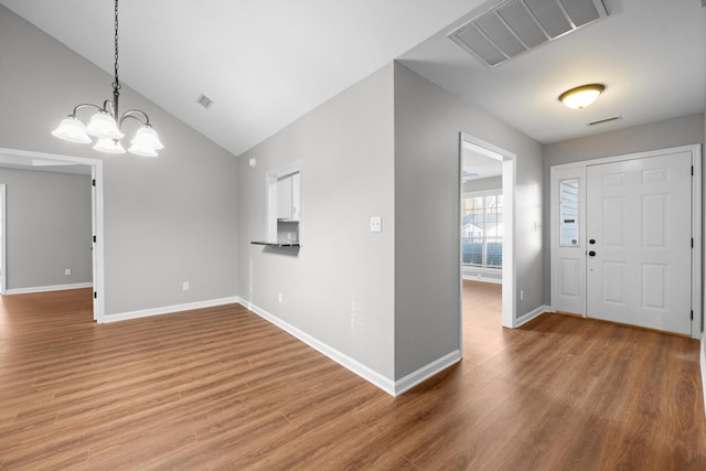 entryway with vaulted ceiling, wood-type flooring, and an inviting chandelier