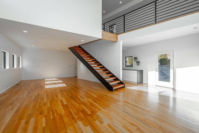 unfurnished living room with a high ceiling and light wood-type flooring