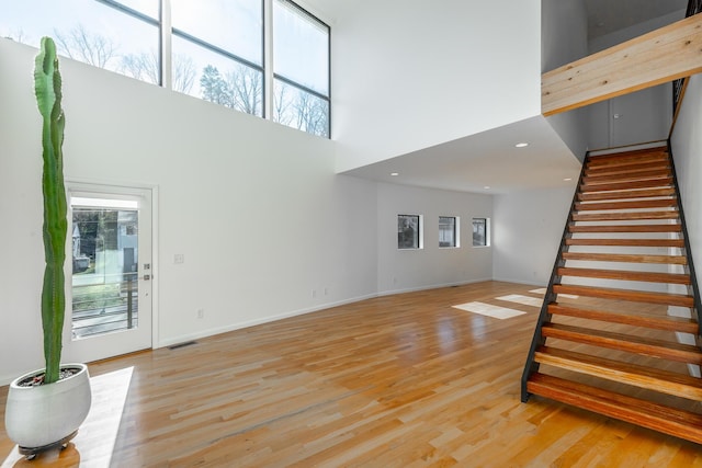 unfurnished living room featuring light hardwood / wood-style flooring and a high ceiling