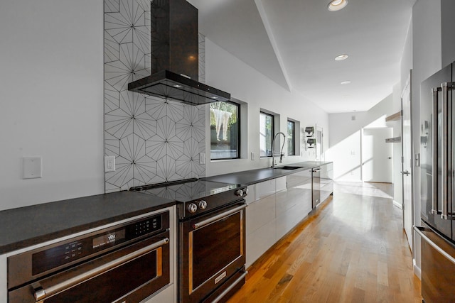 kitchen with sink, white cabinetry, stainless steel appliances, light hardwood / wood-style floors, and exhaust hood