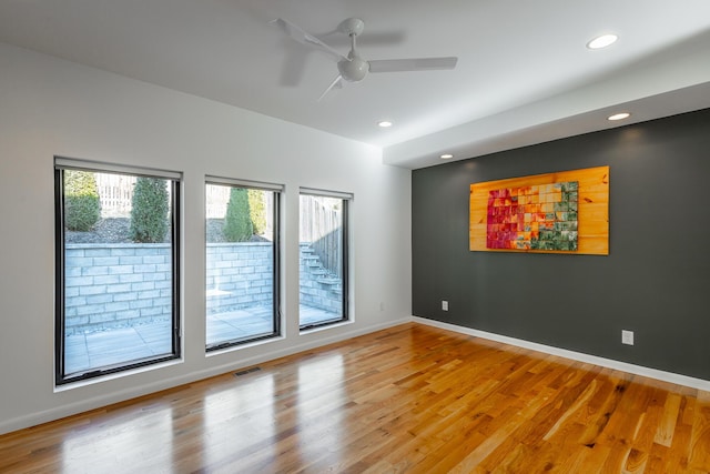 spare room with ceiling fan, a healthy amount of sunlight, and wood-type flooring