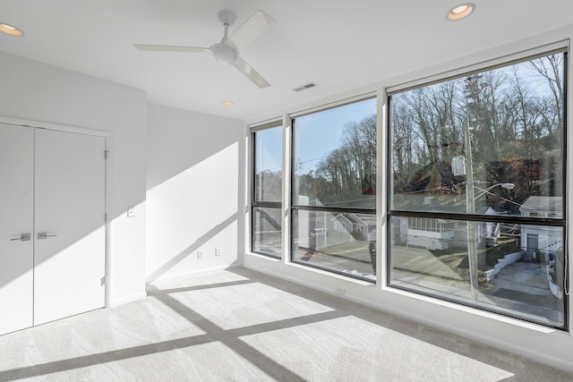 carpeted empty room featuring ceiling fan and a wealth of natural light