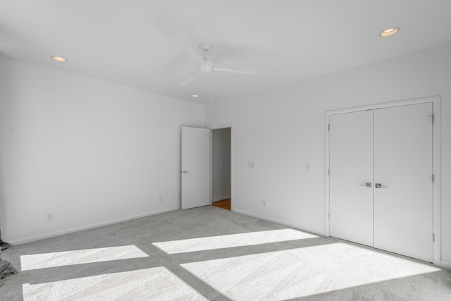 unfurnished bedroom with light carpet, ceiling fan, and a closet