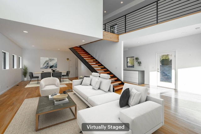 living room featuring a towering ceiling and light hardwood / wood-style flooring