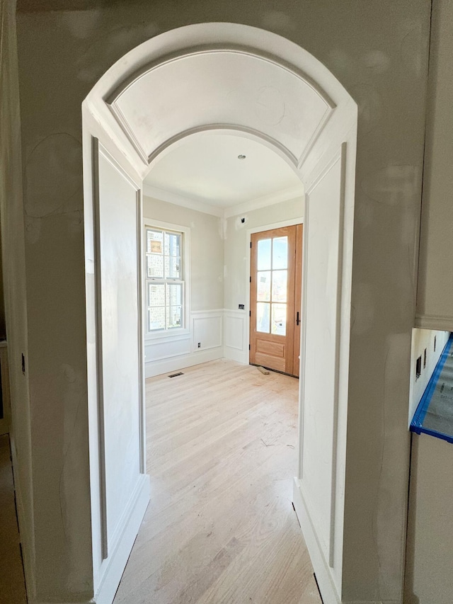 corridor featuring light wood-type flooring and ornamental molding