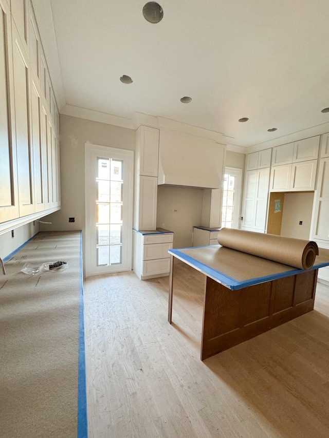 kitchen with light hardwood / wood-style flooring, white cabinets, and ornamental molding