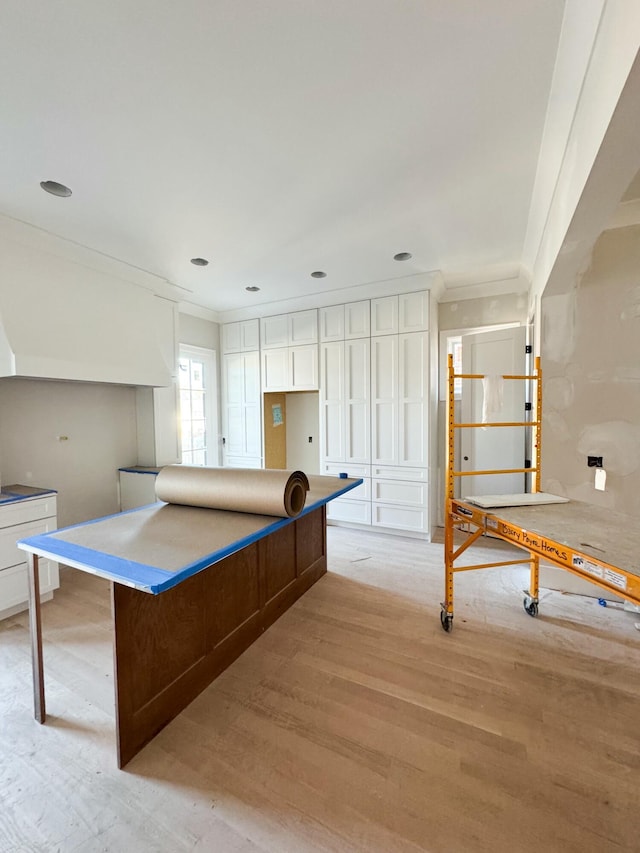 kitchen featuring white cabinets, a center island, light hardwood / wood-style floors, and crown molding