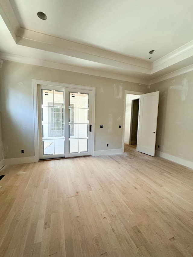 unfurnished room with light hardwood / wood-style floors, crown molding, and a tray ceiling