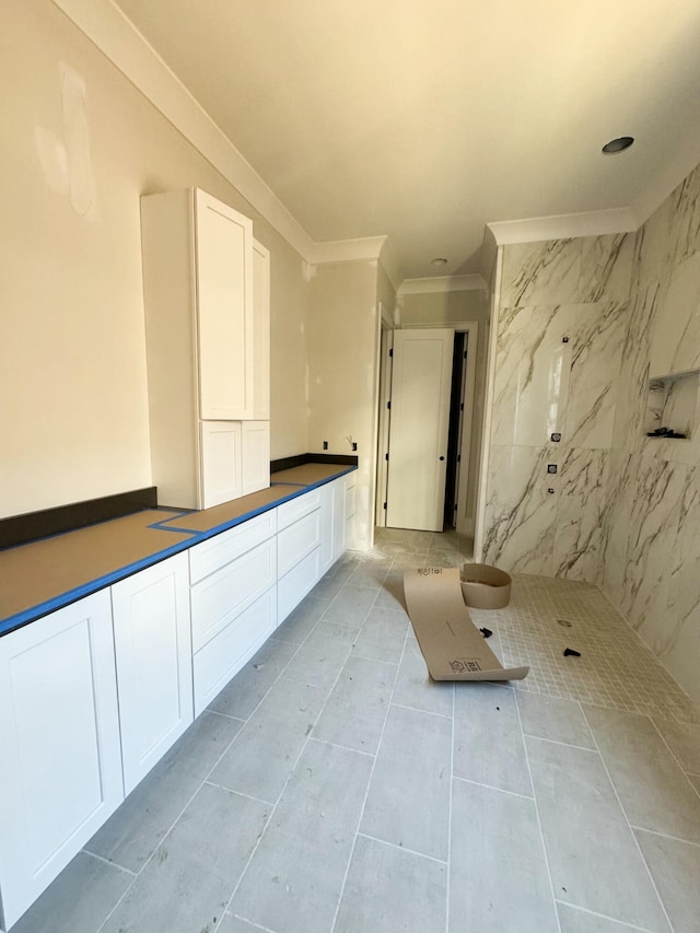 bathroom with a tile shower and crown molding