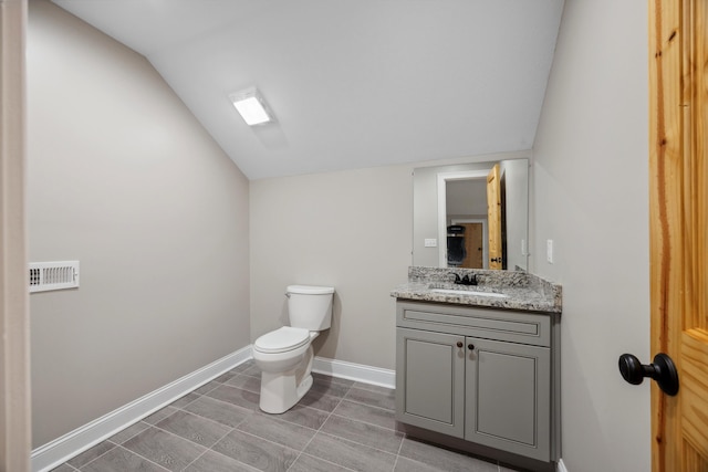 bathroom featuring vanity, toilet, and lofted ceiling