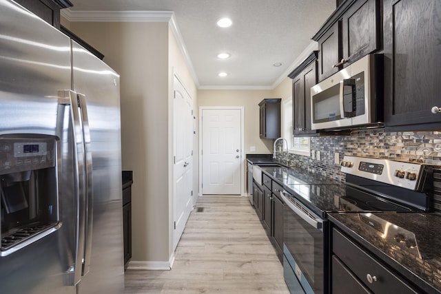 kitchen featuring stainless steel appliances, backsplash, dark stone counters, light hardwood / wood-style floors, and ornamental molding