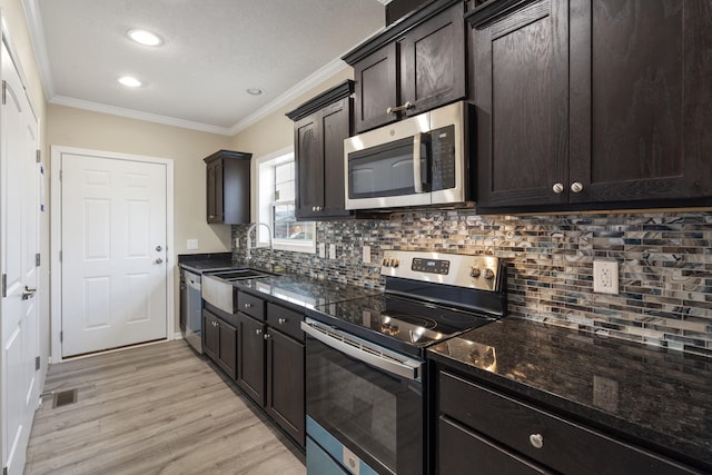 kitchen with appliances with stainless steel finishes, light wood-type flooring, backsplash, crown molding, and sink