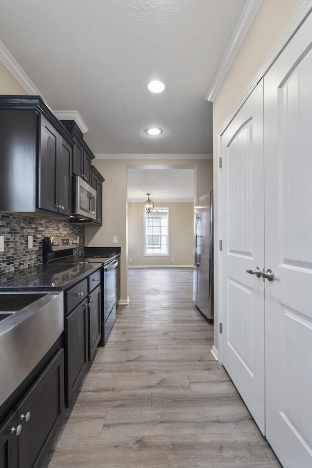 kitchen with an inviting chandelier, backsplash, light hardwood / wood-style floors, appliances with stainless steel finishes, and ornamental molding