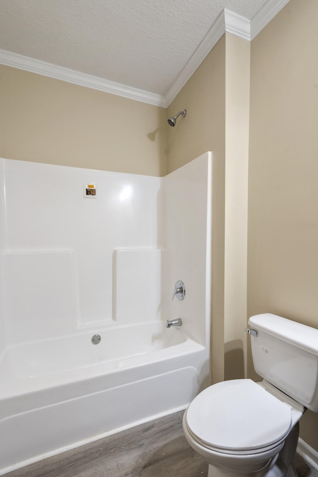 bathroom featuring a textured ceiling, crown molding, shower / bathing tub combination, hardwood / wood-style floors, and toilet