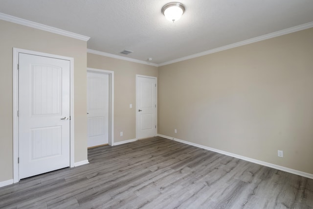 unfurnished bedroom featuring light hardwood / wood-style floors, ornamental molding, and a textured ceiling