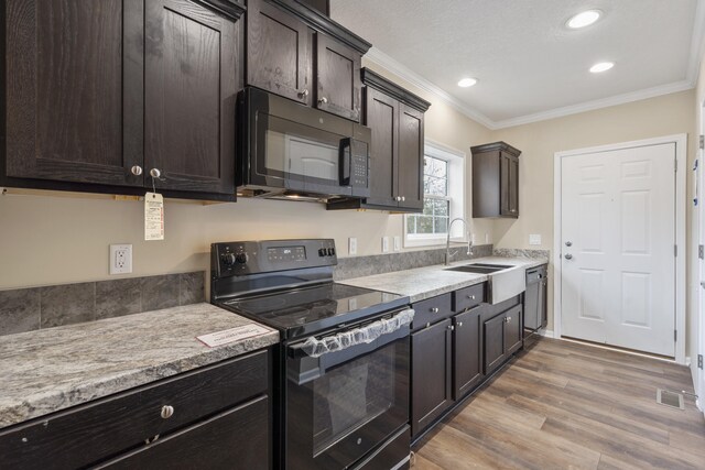 kitchen with black appliances, dark brown cabinetry, light wood-type flooring, and crown molding